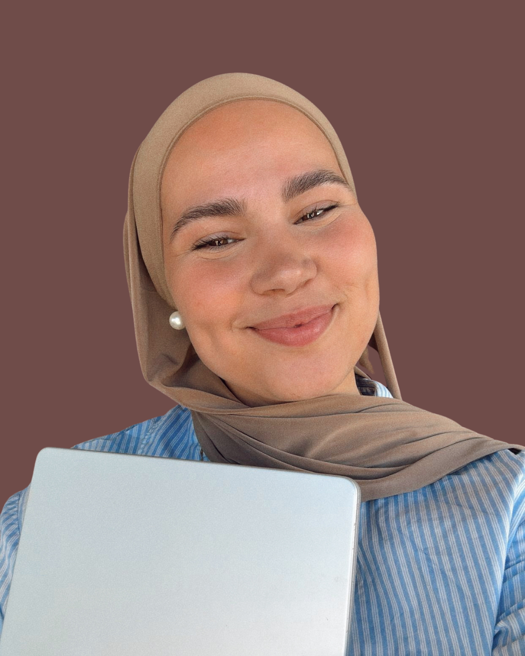 Iman Meskini smiling while holding a laptop